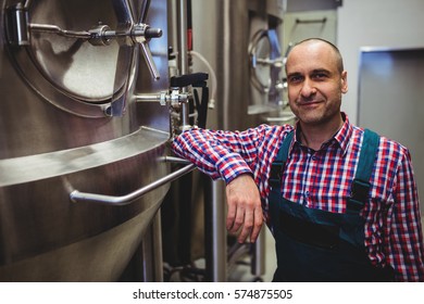 Portrait of smiling manufacturer standing by storage tanks at brewery - Powered by Shutterstock