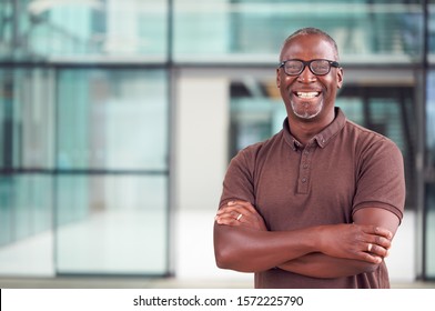 Portrait Of Smiling Mature Businessman Standing In Lobby Of Busy Modern Office - Shutterstock ID 1572225790