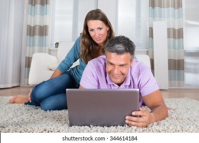 Portrait Of A Smiling Mature Couple Looking At Laptop