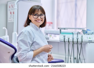 Portrait Of Smiling Mature Female Dentist Looking At Camera In Office
