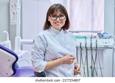 Portrait Of Smiling Mature Female Dentist Looking At Camera In Office
