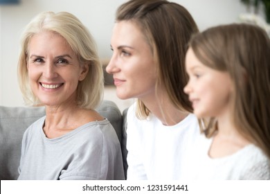 Portrait Of Smiling Mature Grandmother Looking At Camera Near Young Daughter And Kid Granddaughter Looking Forward To Good Future, Three 3 Women Family, Older Elderly Generation Getting Old Concept