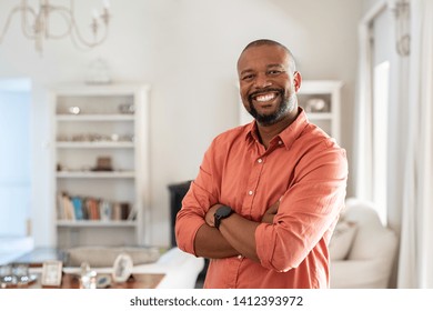 Portrait of smiling mature man with beard standing with crossed arms. Confident african man with folded arms at home looking at camera. Happy senior in casual feeling good. - Powered by Shutterstock