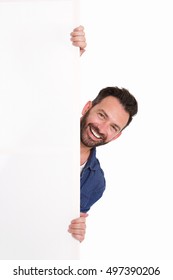 Portrait of smiling mature man peeking over blank poster sign against white background