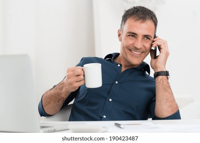 Portrait Of Smiling Mature Man Talking On Cellphone Holding Coffee Cup - Powered by Shutterstock