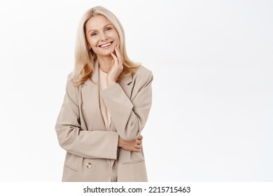 Portrait of smiling mature woman, 50 years old grandmother, standing in trench coat, looking happy, standing over white background - Shutterstock ID 2215715463