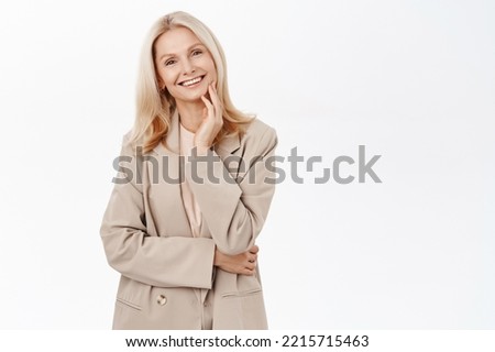 Portrait of smiling mature woman, 50 years old grandmother, standing in trench coat, looking happy, standing over white background