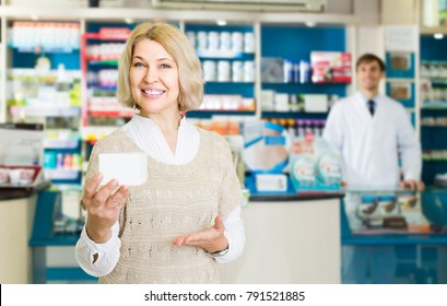 Portrait of smiling mature woman chooses drugs at the pharmacy
