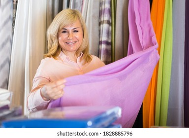 Portrait of smiling mature woman choosing draperies in the store