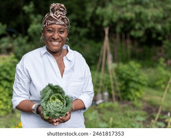Portrait of smiling mature woman holding cabbage in allotment