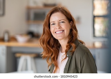 Portrait smiling mature woman looking at camera and big grin  Successful middle aged woman at home smiling  Beautiful mid adult lady and long red hair enjoying whitening teeth treatment 