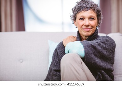 Portrait Of Smiling Mature Woman Sitting On Sofa At Home