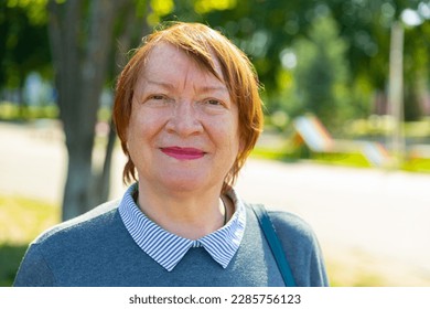 Portrait of a smiling mature woman walking down the street on a summer day. Close-up portrait