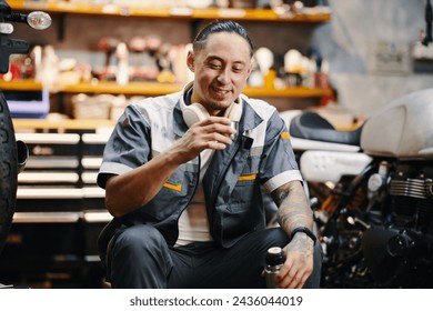 Portrait of smiling mechanic drinking coffee from thermos during break - Powered by Shutterstock