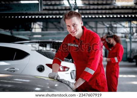 Portrait of smiling mechanic man in red uniform standing around vehicle cars at garage, auto technician checking and repairing maintenance customer car automobile at repair service shop.