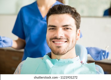 Portrait Of Smiling Mid Adult Man With Dentist Holding Dental Tools At Clinic