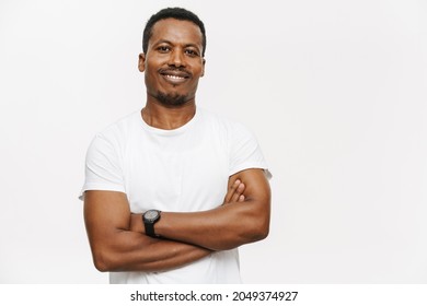 Portrait Of A Smiling Mid Aged African Man In T-shirt Standing Over White Background Arms Folded