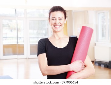 Portrait Of A Smiling Middle Age Woman Holding In Her Hand A Yoga Mat After Doing Yoga. 