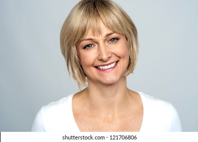 Portrait Of A Smiling Middle Aged Caucasian Woman Isolated Against Grey Background.