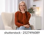 Portrait of smiling middle aged woman on armchair at home