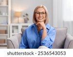 Portrait of smiling middle aged woman sitting on armchair at home