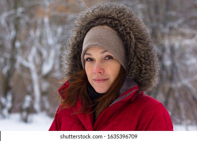 Portrait Of Smiling Middle Aged Woman With Calm Look Looking At Camera In Winter Time In Warm Red Cloth With Hood