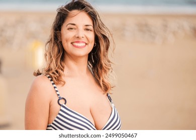 Portrait of smiling middle aged woman wearing a striped bikini on a beach day - Powered by Shutterstock