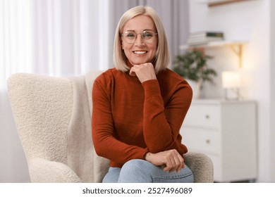 Portrait of smiling middle aged woman on armchair at home - Powered by Shutterstock