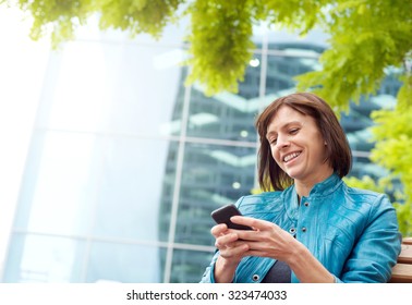 Portrait Of A Smiling Middle Aged Woman Using Mobile Phone Outside