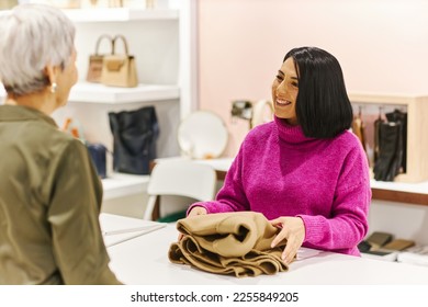 Portrait of smiling Middle Eastern woman working in clothing boutique and greeting customer - Powered by Shutterstock