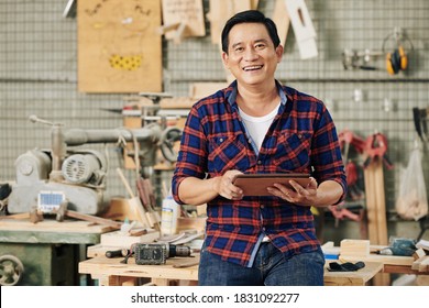 Portrait of smiling middle-aged carpenter with digital tablet standing in his carpentry shop - Powered by Shutterstock