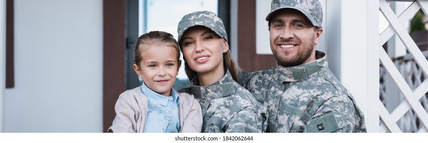 Portrait Of Smiling Military Mother And Father With Daughter Looking At Camera With House On Background, Banner