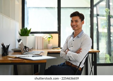 Portrait of smiling millennial asian businessman sitting with arms crossed gesture and smiling to camera - Shutterstock ID 2254636659