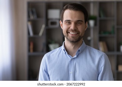 Portrait Of Smiling Millennial Generation Man Posing In Modern Living Room. Handsome Young Male Homeowner Looking At Camera, Standing Indoors, Real Estate Services, Property Ownership Concept.