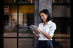Portrait Of A Smiling Mixed Races Business Woman, Using Tablet Outside The Building