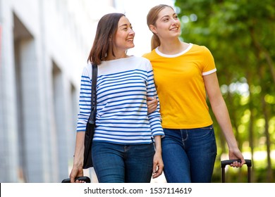 Portrait Of Smiling Mother And Daughter Walking Outdoors With Bags