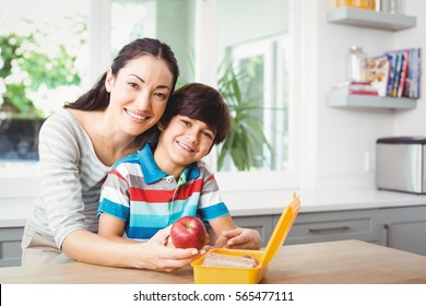 Portrait Of Smiling Mother And Son With Lunch Box At Table