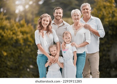 Portrait of a smiling multi generation caucasian family standing close together in the garden at home. Happy adorable girls bonding with their mother, father, grandfather and grandmother in a backyard - Powered by Shutterstock