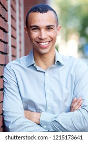 Portrait Of Smiling North African Businessman Leaning On Wall Outdoors