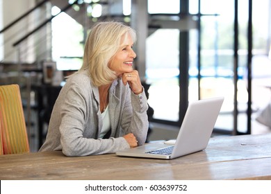 Portrait Of Smiling Older Woman Working Laptop Computer Indoors