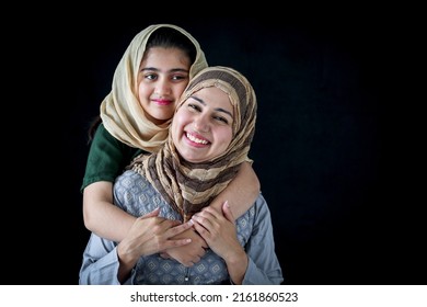 Portrait Of Smiling Pakistani Muslim Woman With Daughter, Adorable Beautiful Eyes Kid Girl With Hijab Hugs Mother, Warm Love Of Mom And Daughter, Happy Lovely Islamic Family On Dark Black Background.