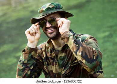 Portrait Of Smiling Park Ranger In Military Uniform And Sunglasses On Green Background.