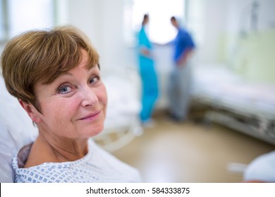 Portrait Of Smiling Patient Sitting On Bed In Hospital
