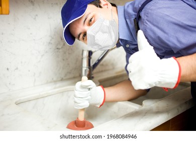 Portrait Of A Smiling Plumber Using A Plunger, Covid Or Coronavirus Concept