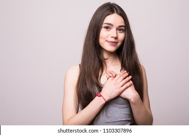 Portrait Of Smiling Positive Young Woman Keeps Hands On Chest, Expresses Sympathy. Kind Hearted Friendly Nice Girl Shows Kindness, Wearing Blank White T-shirt