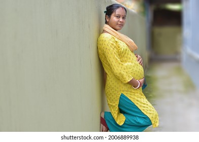 Portrait of a smiling, pregnant Indian woman holding her belly. Baby careing cocept.