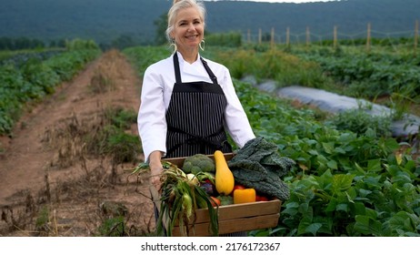 Portrait Of Smiling, Pretty, Caucasian, Female Chef Carrying Fresh Picked Vegetables Walking Towards Camera On A Farm For Farm To Table At Sunrise Sunset.