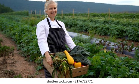 Portrait Of Smiling, Pretty, Caucasian, Female Chef Carrying Fresh Picked Vegetables Walking Towards Camera On A Farm For Farm To Table At Sunrise Sunset.