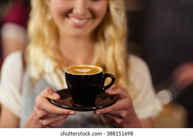 Portrait of smiling pretty customer holding cup of coffee at coffee shop - Shutterstock ID 388151698