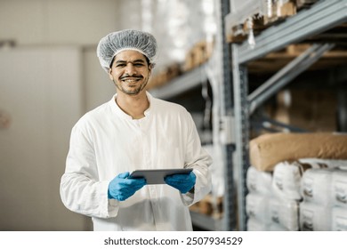 Portrait of smiling professional food factory warehouse worker using tablet app for inventorying goods. - Powered by Shutterstock